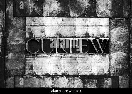 Foto di vere e proprie lettere di typeset che formano il testo Curfew su sfondo bianco e nero vintage ruvido color argento Foto Stock