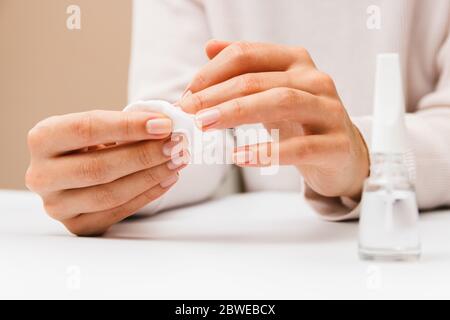 manicure a casa. closeup mani donna teneri rimuovere vernice da unghie utilizzando il disco di cotone Foto Stock