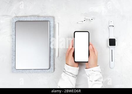 Disposizione piatta di dispositivi elettronici portatili - computer tablet, stilo, auricolari wireless e orologio da polso intelligente su sfondo in cemento. Derisione di fe Foto Stock