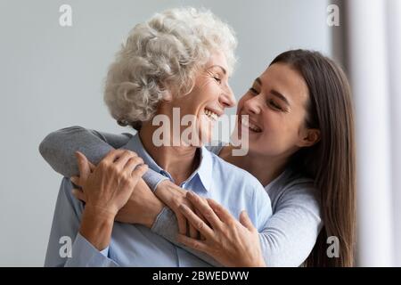 Amorevole ragazza allegra grunnup abbraccia la madre anziana ridendo divertendosi Foto Stock