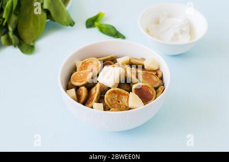 Spinaci frittelle di cereali in un recipiente bianco su sfondo azzurro. Vista dall'alto, primo piano. Foto Stock