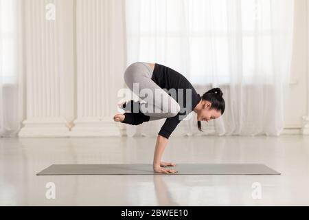 Bella giovane donna asiatica che lavora fuori, facendo l'esercitazione di yoga, il supporto del handstand asana, l'esercitazione per le armi e la resistenza dei polsi, la posa del Crane Crane Crow, Bakasana Foto Stock