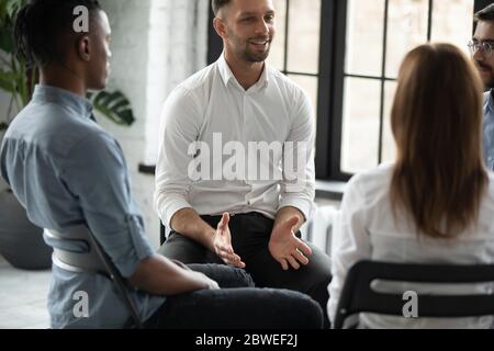 Psicologo sorridente e fiducioso che parla alla sessione di terapia di gruppo Foto Stock