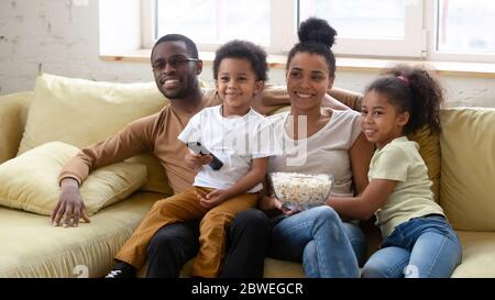 Famiglia africana intera trascorrere il fine settimana a casa guardando la TV Foto Stock