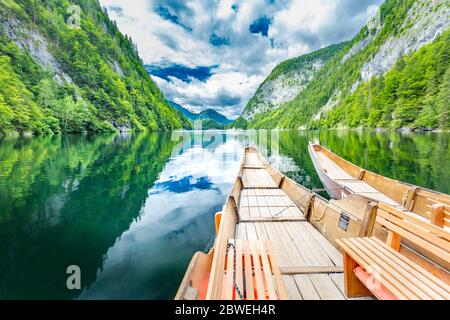 Splendida vista della tradizionale barca a remi in legno su Scenic. Il lago di montagna estivo passa la luce panoramica del mattino alle nuvole all'alba su alberi blu cielo verde Foto Stock