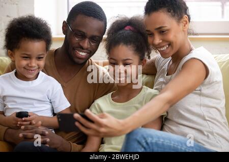 Famiglia africana con bambini che guardano video divertenti sullo smartphone Foto Stock