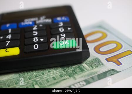 Concetto di bonifico bancario e di saldo del conto: Calcolatore isolato con banconota da 100 dollari USA, focalizzazione sul pulsante verde o.k Foto Stock