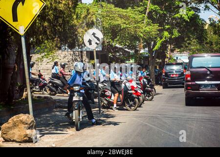 BALI, INDONESIA - 30 novembre 2019: I piloti di scooter aspettano all'incrocio. Traffico scooter sulla strada di Bali. Indonesia Foto Stock
