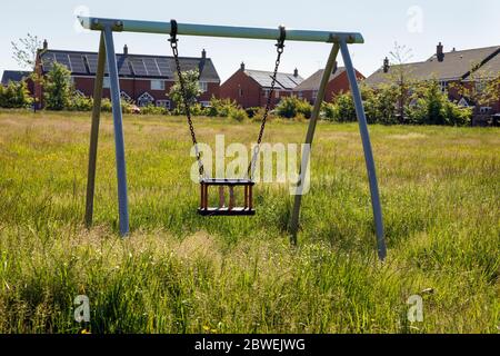 Erba lunga in un parco giochi chiuso per bambini dopo 10 settimane di chiusura del coronavirus, Ashbourne, Derbyshire, giugno 2020 Foto Stock