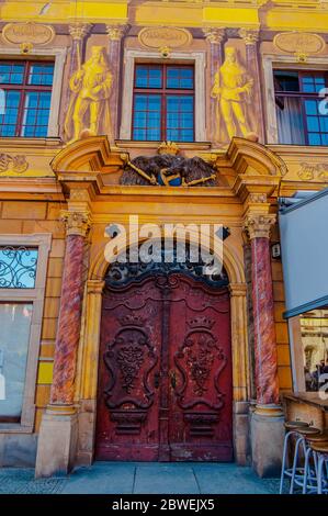 Wroclaw, Polonia - 2012: Arco di stucco giallo con porta in legno rosso splendidamente decorata con decorazioni curve Foto Stock