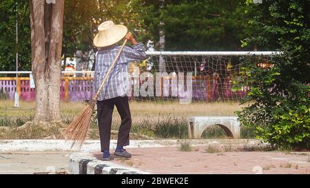 Vecchia pulitrice femminile e tenendo una spazzata al parco. Foto Stock