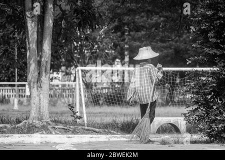 Vecchia donna pulitore e tenendo una spazzata al Park.Black e bianco stile Foto Stock