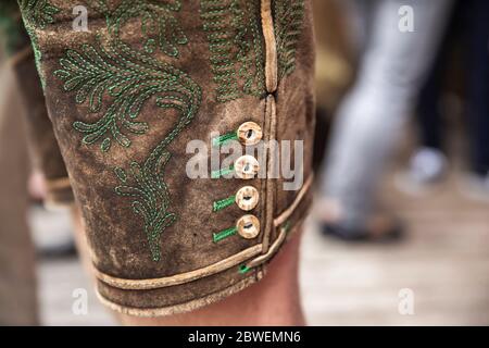 primo piano di un tradizionale pantaloni in pelle austriaca con ricamo verde e pulsante a tromba Foto Stock