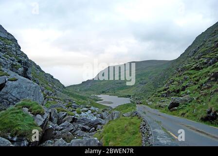 Strada attraverso il paesaggio con un lago sullo sfondo, Irlanda Foto Stock