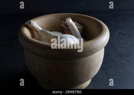 gruppo di teste di aglio in una ciotola di legno con fondo nero Foto Stock