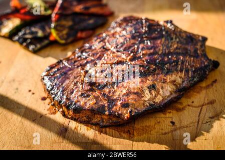 Alla griglia marinati succosa bistecca angus fiancheggiano bistecca su tavola di legno. Terminato mezzo succosa carne di rare è a riposo prima che esso venga tagliato a fette e. Foto Stock