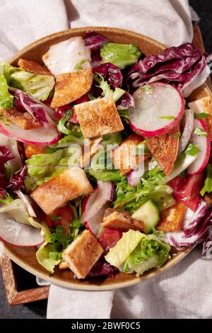 Insalata tradizionale di Fattoush mediorientale con pane pita, verdure fresche e salsa di sumac al limone su sfondo grigio scuro vista dall'alto Foto Stock