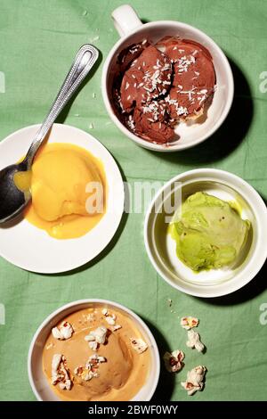 Ciotole di vari zucchero vegano senza sorbetto gelato scoop su sfondo verde top vista close-up.concetto di dessert sano Foto Stock