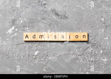 Parola DI AMMISSIONE scritta su blocco di legno. Testo DI AMMISSIONE su tabella di cemento per il vostro desing, concetto. Foto Stock