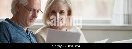 I coniugi anziani leggono il rendiconto bancario, gestiscono il bilancio familiare si sente soddisfatto Foto Stock