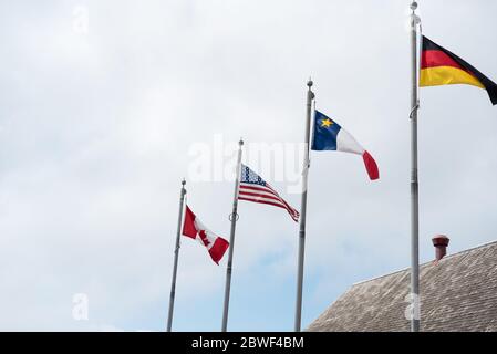 Bandiere nazionali su pali che ondano nel vento contro lo sfondo del cielo. Bandiera del Canada, Stati Uniti, Germania. Concetto di relazioni internazionali Foto Stock