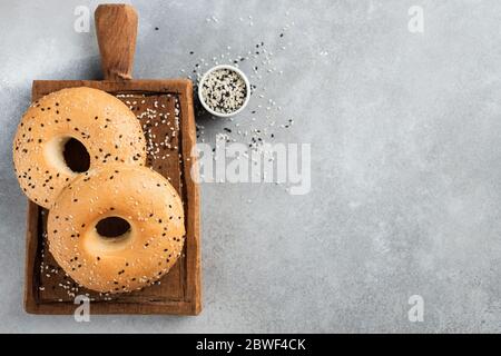 Due bagel di sesamo su sfondo grigio in cemento, spazio per la copia della vista dall'alto per testo o disegno. Bagel americani appena sfornati Foto Stock