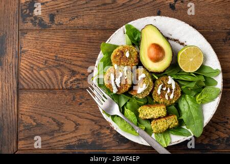 Falafel avocado di ceci con Spinaci e Salsa di Cashew su sfondo tavola di legno. Spazio copia vista superiore Foto Stock