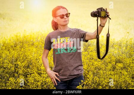 Donna che scatta una fotografia selfie, indossando una t-shirt con lo slogan "Life is't like". Foto Stock