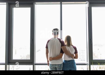 Giovane bella coppia stare vicino Window abbracciare, Happy Smile uomo ispanico e Donna Lovers abbraccio retro Vista posteriore Foto Stock