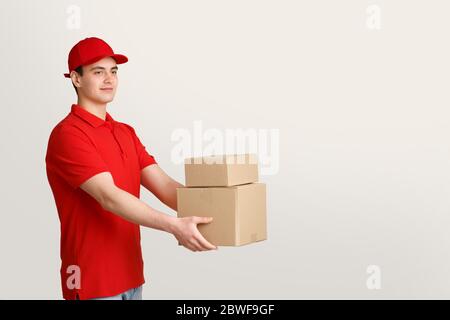 Concetto di consegna, posta e spedizione. Il corriere in uniforme tiene le scatole nelle mani Foto Stock