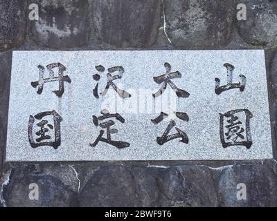Primo piano della targa a Kanagawa, Giappone. I testi in giapponese significano: Tanzania-Ōyama quasi-Parco Nazionale. Foto Stock