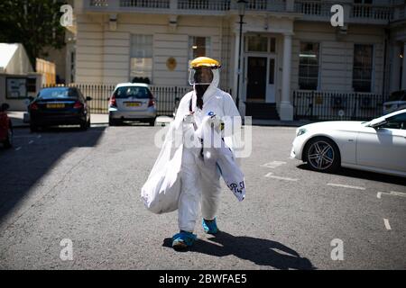 Un uomo che indossa un PPE pieno cammina attraverso Knightsbridge, Londra, dopo l'introduzione di misure per portare l'Inghilterra fuori dal blocco. Foto Stock