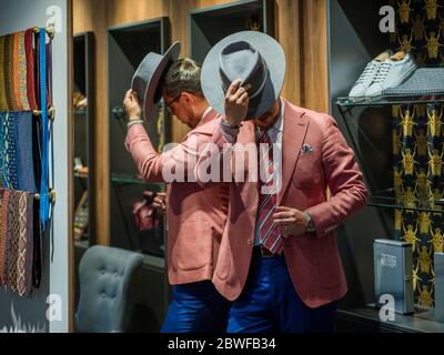 Uomo in abito nascondendo faccia dietro il suo cappello Foto Stock