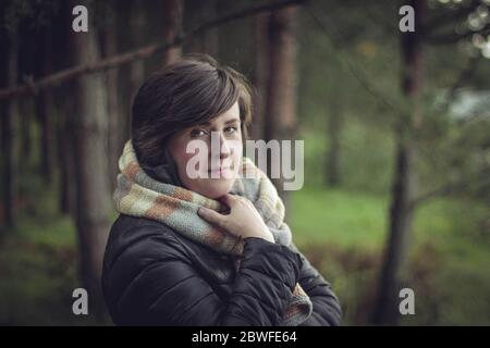 Ritratto di una giovane ragazza che cammina nel parco. La ragazza si avvolse in una sciarpa calda.Beautiful ragazza elegante sta riposando nel parco autunnale. Foto Stock