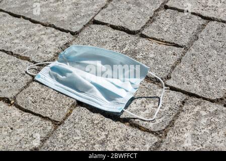 Maschera usa e getta caduto a terra in strada. Concetto di inquinamento ambientale Foto Stock
