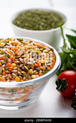 Variopinti fagioli o lenticchie e semi interi o cereali in ciotola con verdure fresche. Foto Stock