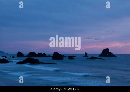 Formazioni rocciose nell'Oceano Pacifico viste da Cannon Beach al tramonto, Oregon, USA Foto Stock