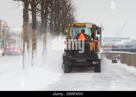 Veicolo per spazzaneve che rimuove la neve dopo la pioggia/tempesta di neve in movimento. Pulizia urgente della strada della città alla luce del giorno. Nevicate pesanti. Periodo invernale Foto Stock