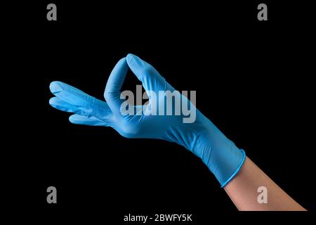 Mano del medico in guanti medici sterili in gesto di OK isolato su nero Foto Stock