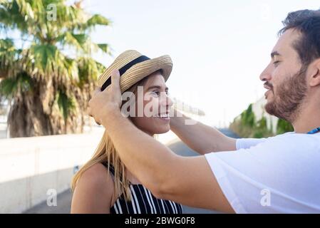 Uomo che mette cappello sulla testa della ragazza mentre si trova in città Foto Stock