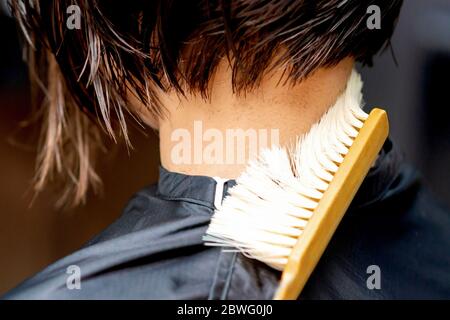 Primo piano di parrucchiere pulisce il collo della donna dai capelli cuted a pennello. Foto Stock