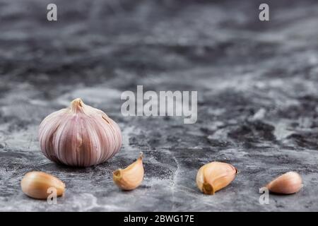Aglio fresco su tavola vintage. Bulbo e guanti all'aglio sbucciati su grana di granito Foto Stock