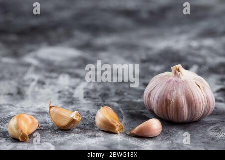 Aglio fresco su tavola vintage. Bulbo e guanti all'aglio sbucciati su grana di granito Foto Stock