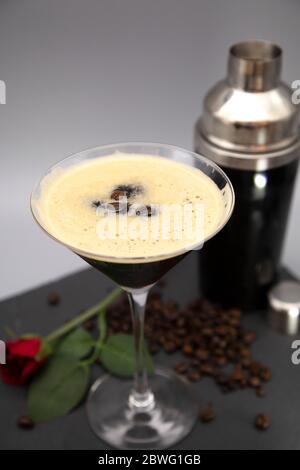 Un espresso Martini servito in un bicchiere martini e guarnito con chicchi di caffè arrosto. Il bicchiere è visibile con chicchi di caffè appena tostati. Foto Stock