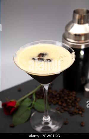 Un espresso Martini servito in un bicchiere martini e guarnito con chicchi di caffè arrosto. Il bicchiere è visibile con chicchi di caffè appena tostati. Foto Stock