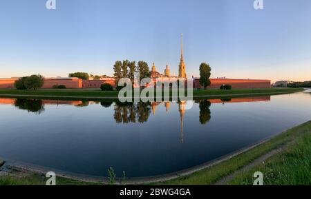 Russia, San Pietroburgo, il suggestivo riflesso della Fortezza di Pietro e Paolo nel passaggio kronverksky su un tramonto, acqua calma, cielo blu, parete di Foto Stock