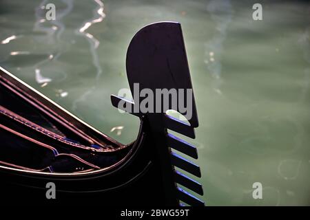 Primo piano sulla prua di una gondola a Venezia, lungo il canale di acqua di mare, in una soleggiata giornata invernale. Concentrarsi solo sul prow. Foto Stock