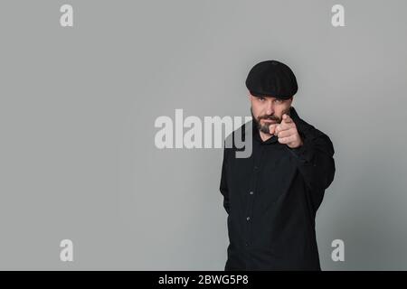 Bell'uomo di mezza età in una camicia bianca mostra un dito sulla fotocamera su uno sfondo grigio Ritratto di un uomo anziano che punta a voi leanin Foto Stock