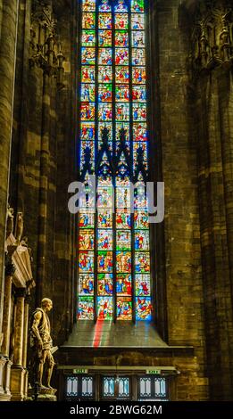 Milano, Lombardia, Italia - 2019 aprile: Statua di San Bartolomeo all'interno del Duomo di Milano con colorata vetrata religiosa sul retro Foto Stock