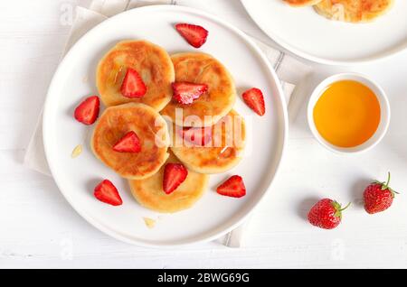 Cottage cheese pancake con fette di fragola e miele. Una sana prima colazione. Vista superiore, laici piatta Foto Stock